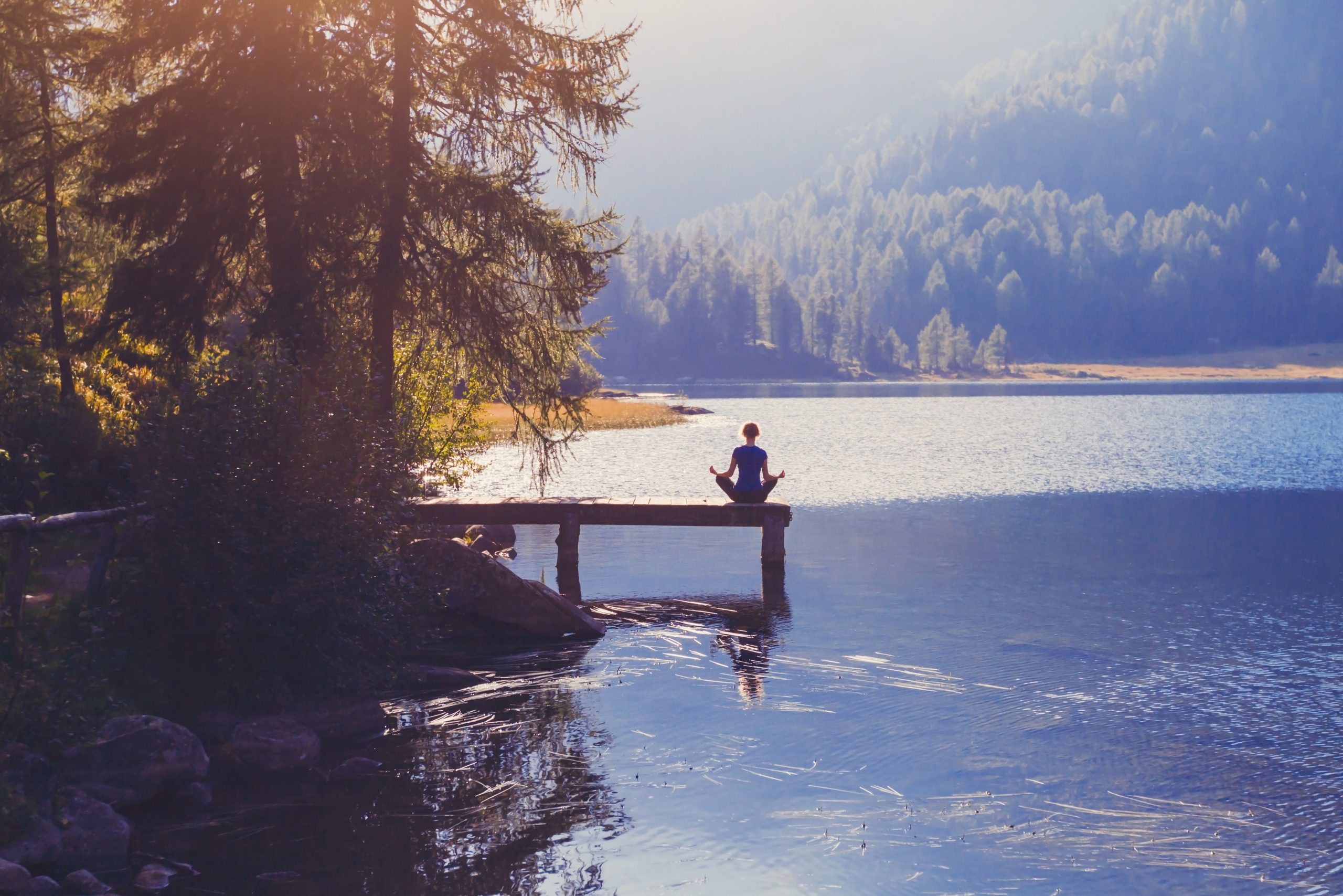woman meditating by a lake
