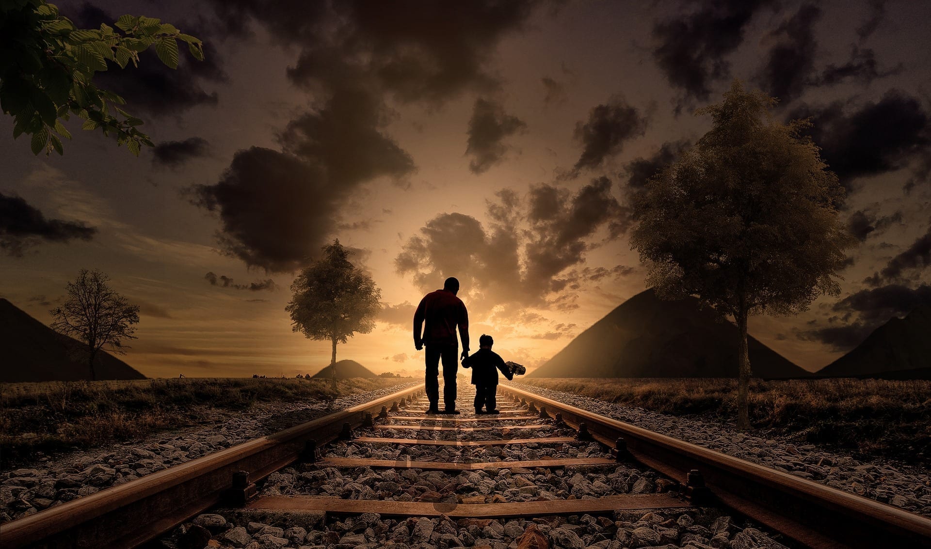 man and child walk on train tracks at sunset